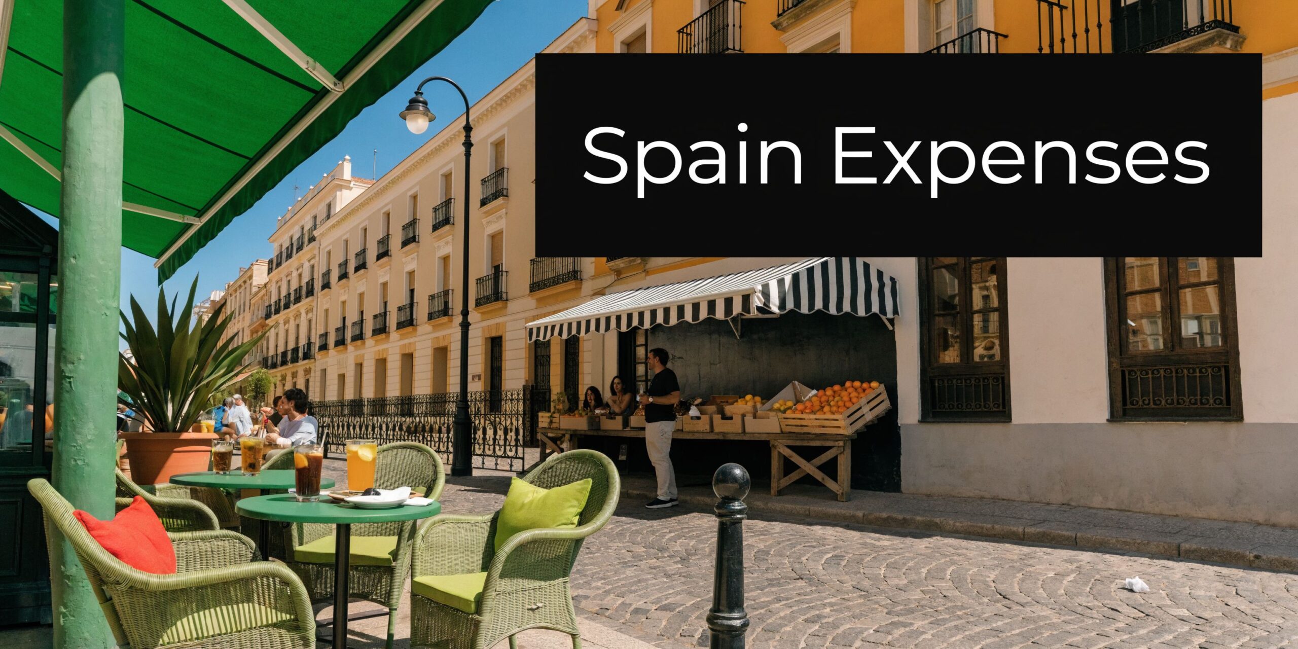 People enjoying drinks at an outdoor cafe on a cobblestone street in a sunny Spanish town.